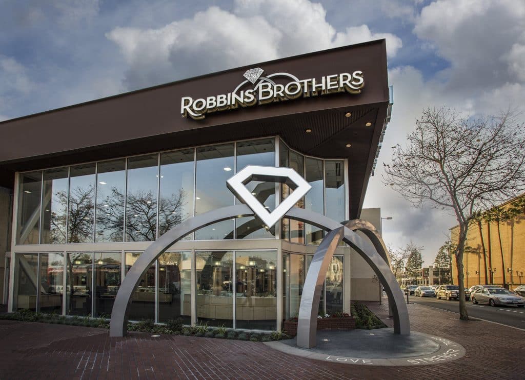 Exterior of a Robbins Brothers jewelry store with a large diamond logo above the entrance. The building has glass windows and is located on a street corner. Exterior of a Robbins Brothers jewelry store with a large diamond logo above the entrance. The building has glass windows and is located on a street corner.