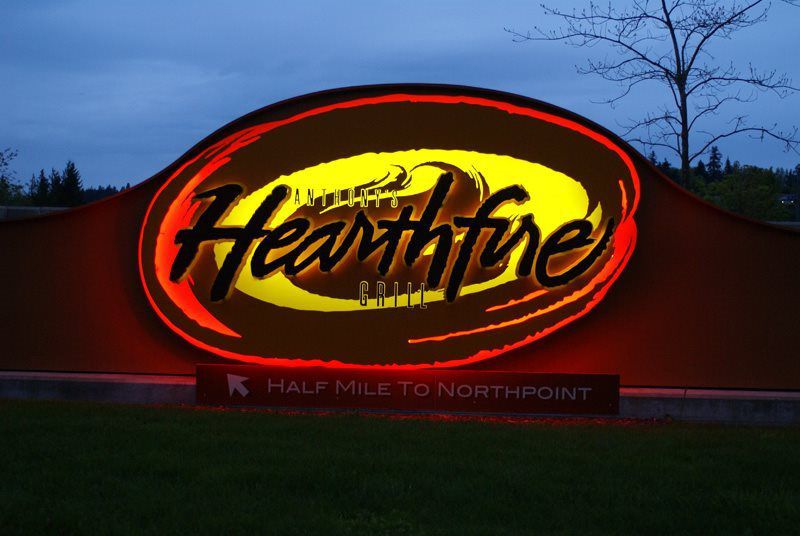 Illuminated sign for Anthony's Hearthfire Grill, featuring bold lettering and a background that transitions from red to yellow. A directional arrow points "Half Mile to Northpoint. Illuminated sign for Anthony's Hearthfire Grill, featuring bold lettering and a background that transitions from red to yellow. A directional arrow points "Half Mile to Northpoint.