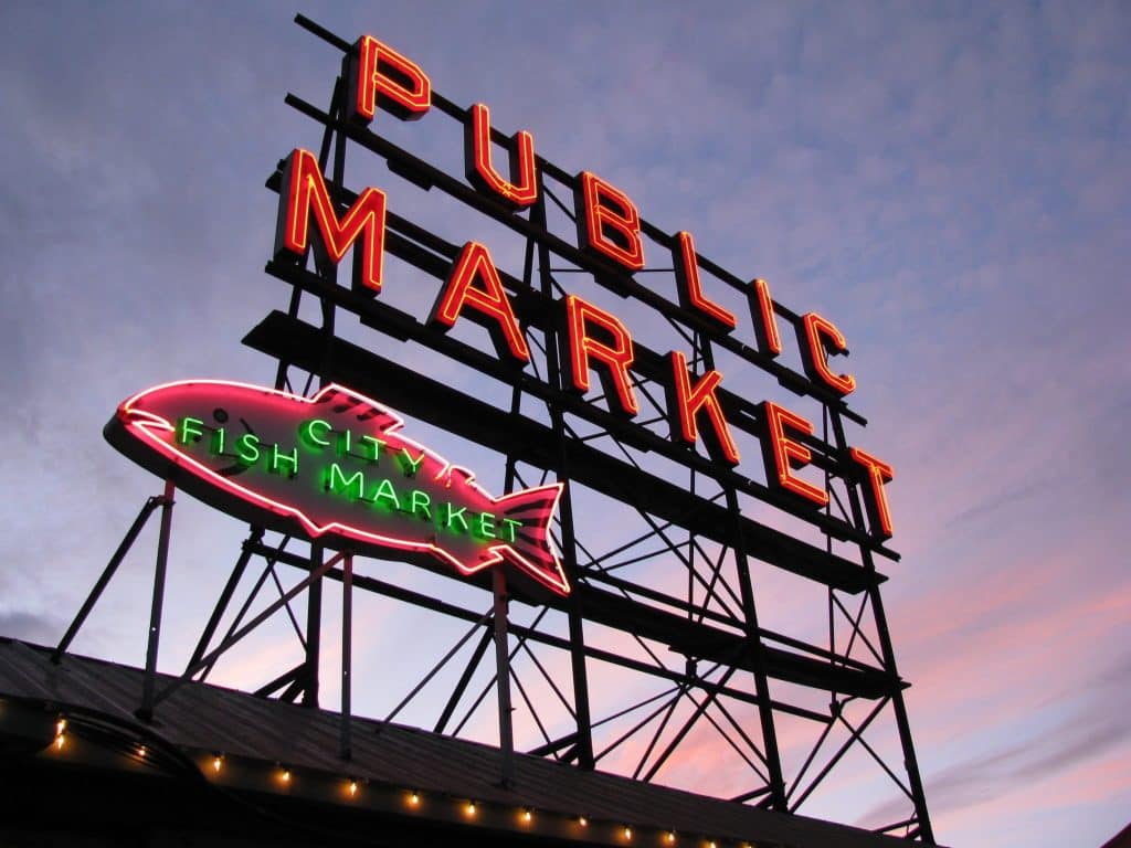 Seattle's Neon illuminates the twilight sky with glowing signs reading "Public Market" and "City Fish Market" atop a bustling building, capturing the city's vibrant charm. Seattle's Neon illuminates the twilight sky with glowing signs reading "Public Market" and "City Fish Market" atop a bustling building, capturing the city's vibrant charm.