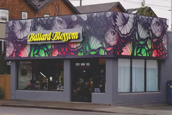A flower shop with a colorful floral mural on the facade and the sign "Ballard Blossom" above the entrance.
