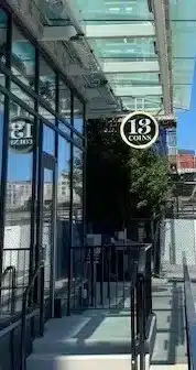 Exterior view of a building with a glass entrance featuring a "13 Coins" sign. Exterior view of a building with a glass entrance featuring a "13 Coins" sign.