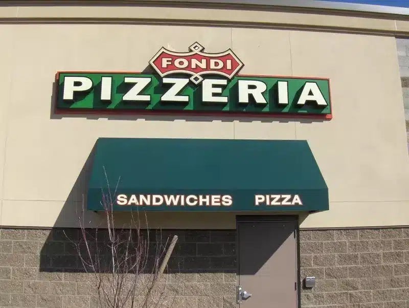 Exterior of a building with a sign reading "Fondi Pizzeria." Below it, an awning displays the words "Sandwiches" and "Pizza. Exterior of a building with a sign reading "Fondi Pizzeria." Below it, an awning displays the words "Sandwiches" and "Pizza.