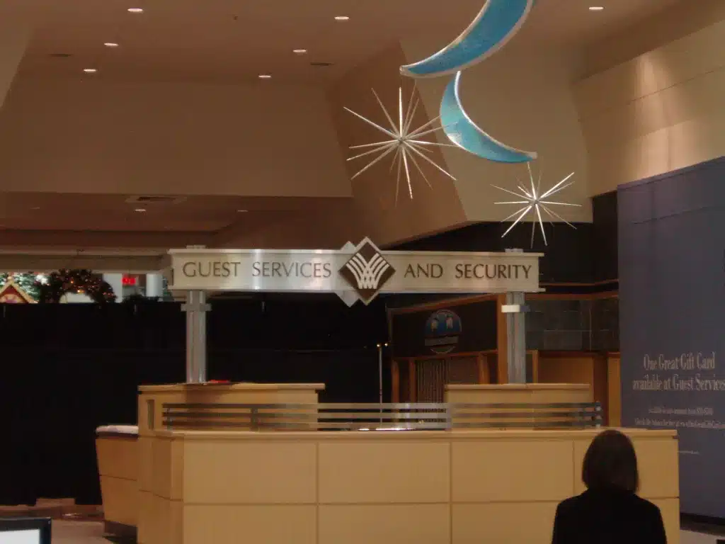 OLYMPUS DIGITAL CAMERA Guest services and security desk in a shopping mall, with decorative stars and moon above.